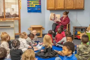 A Montessori teacher guiding a child through early reading exercises using movable alphabet letters.