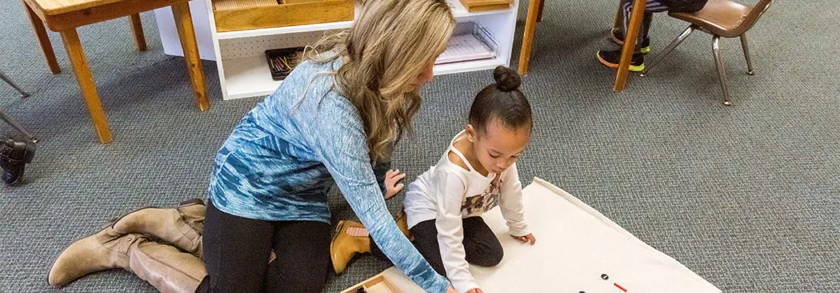 Children engaged in collaborative learning, using Montessori zoology puzzles to identify animals.