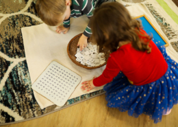 A child working independently with Montessori pink tower cubes to develop spatial awareness.