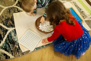 A child working independently with Montessori pink tower cubes to develop spatial awareness.