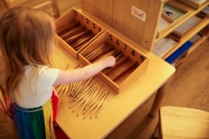 Children using Montessori knobbed cylinders to refine their sense of size and dimension.