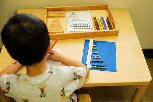 Children developing fine motor skills through Montessori lacing and threading activities.