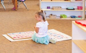A student practicing balance and coordination by walking on a Montessori classroom line.