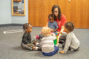 A Montessori teacher guiding a child through early reading exercises using movable alphabet letters.