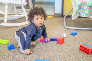 A child concentrating on a practical life task, using a small broom and dustpan to clean up.