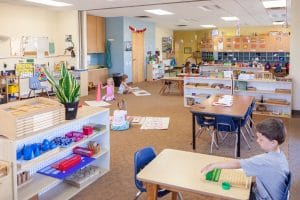 Children using Montessori knobbed cylinders to refine their sense of size and dimension.