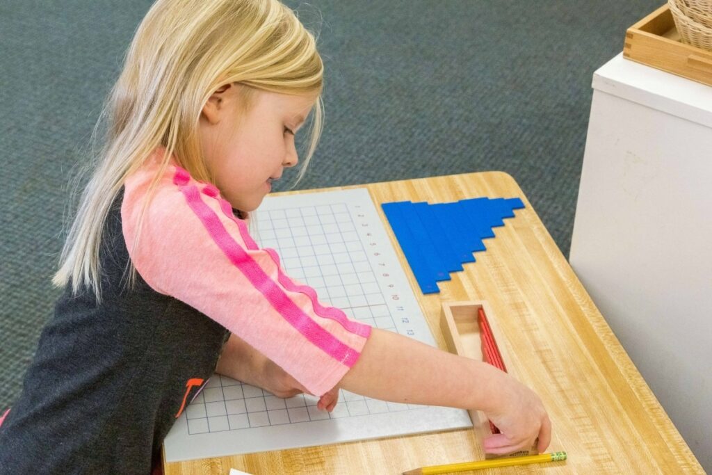 A child using Montessori binomial cubes to learn about algebraic concepts through hands-on exploration.